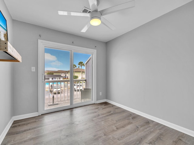 unfurnished room with a ceiling fan, visible vents, wood finished floors, and baseboards