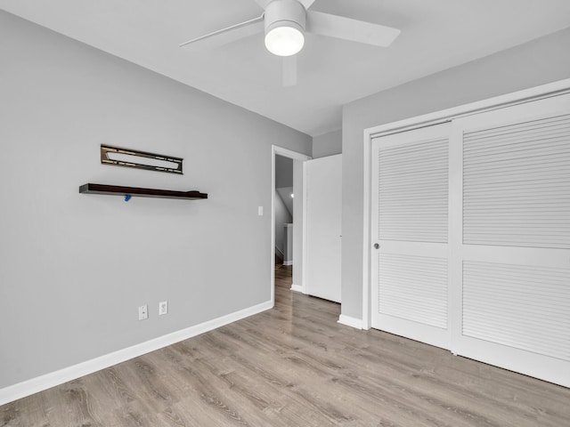 unfurnished bedroom featuring a closet, baseboards, wood finished floors, and a ceiling fan