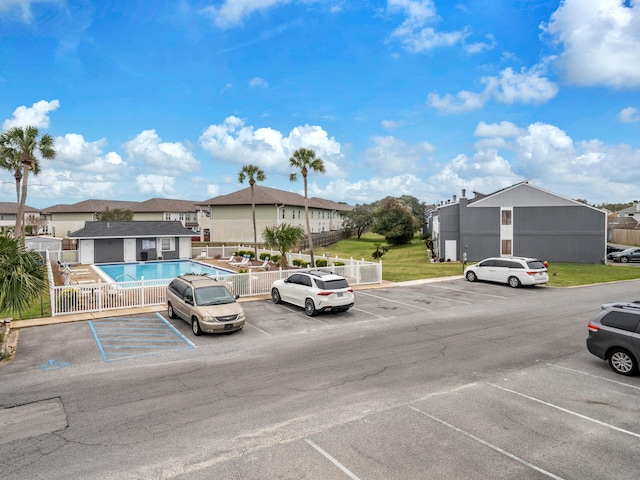 uncovered parking lot featuring a residential view, a community pool, and fence