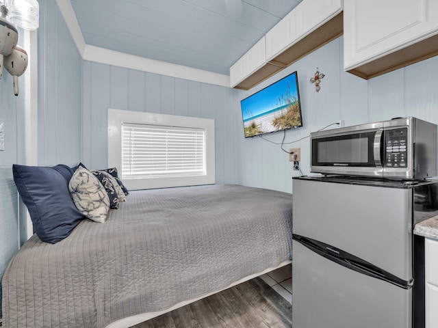 bedroom with dark wood-style flooring and stainless steel refrigerator