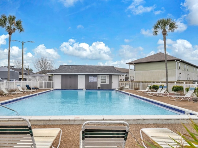 community pool with a patio area and fence