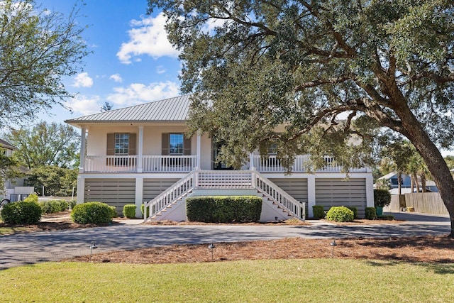 4077 N Indian Byu, Destin, FL 32541 - raised beach house featuring stairs, a porch, stucco siding, metal roof, and a front lawn
