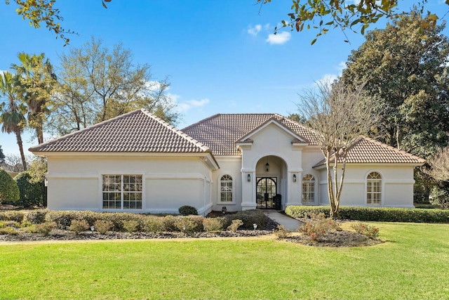 mediterranean / spanish-style home featuring a front lawn, a tiled roof, and stucco siding