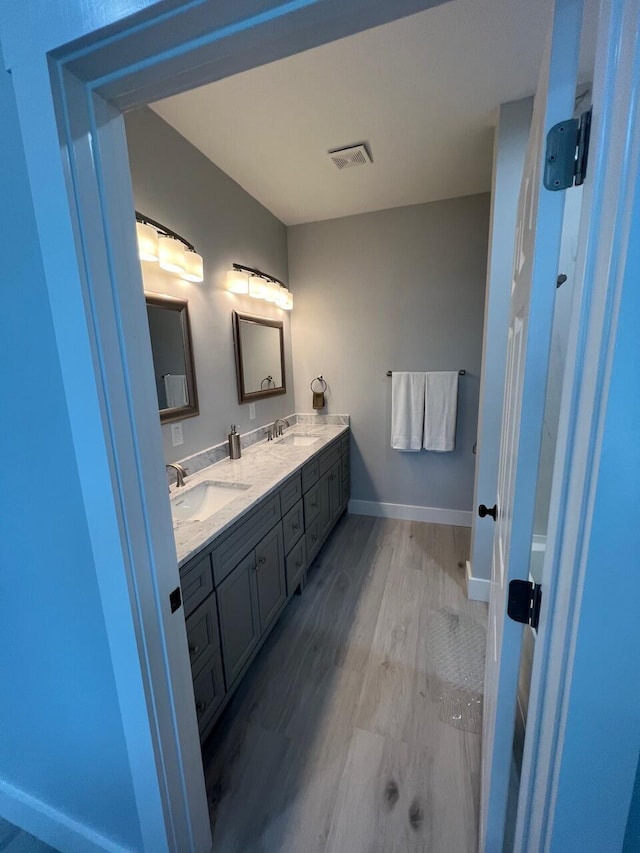 full bathroom featuring visible vents, wood finished floors, baseboards, and a sink