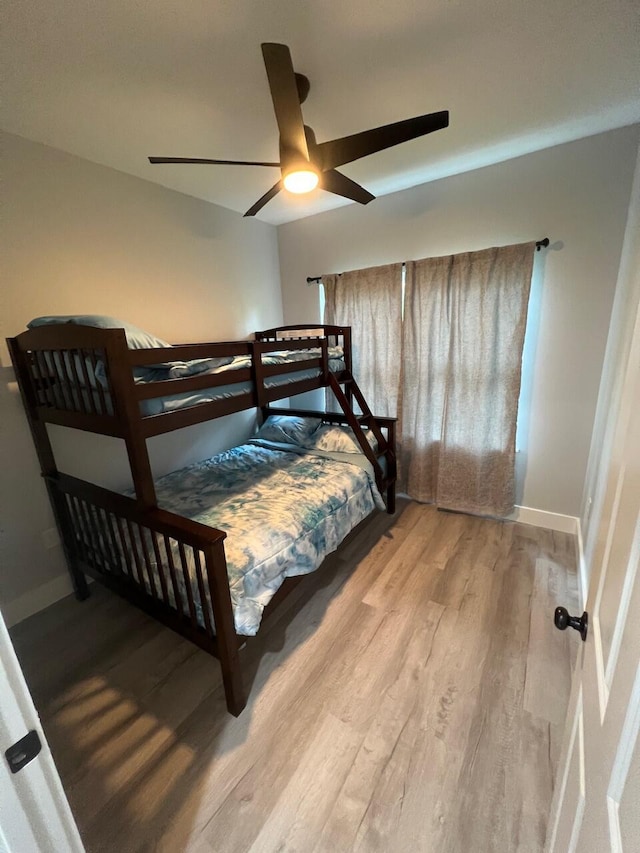 bedroom featuring a ceiling fan, baseboards, and light wood finished floors