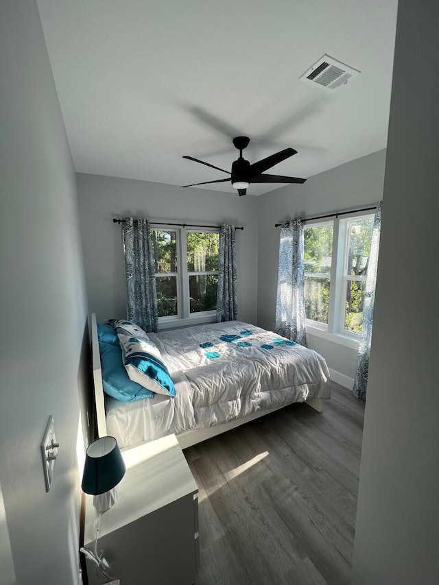 bedroom with ceiling fan, visible vents, baseboards, and dark wood-style floors