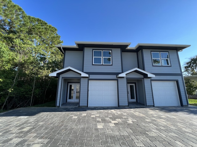 view of front of home with a garage, decorative driveway, and french doors