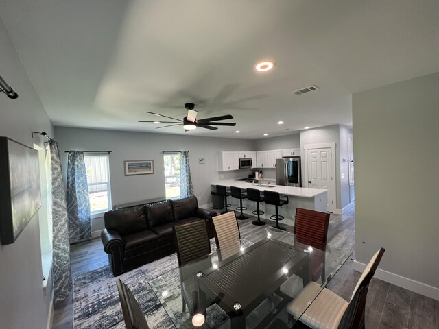 living room featuring visible vents, baseboards, wood finished floors, and a ceiling fan