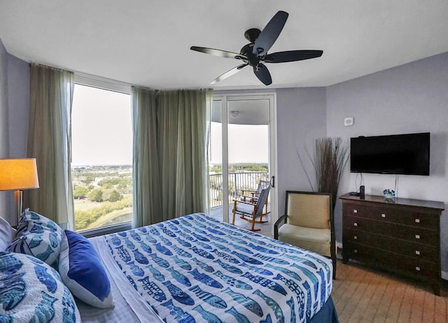 bedroom featuring expansive windows, wood finished floors, a ceiling fan, and access to outside