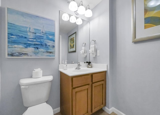 bathroom featuring baseboards, toilet, and vanity