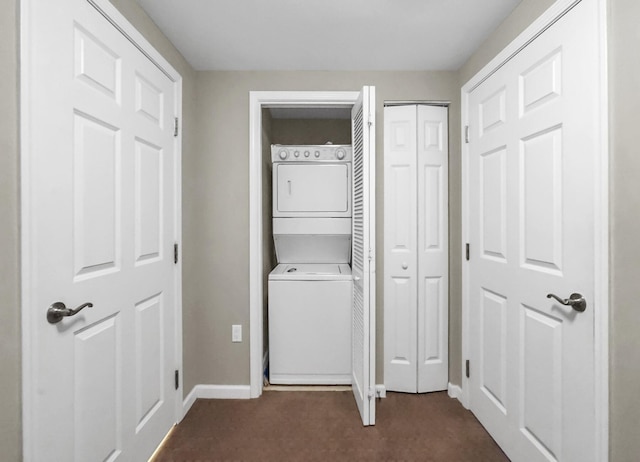 clothes washing area featuring laundry area, baseboards, stacked washer and clothes dryer, and dark carpet