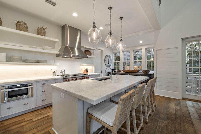 kitchen with visible vents, a sink, wall chimney range hood, appliances with stainless steel finishes, and open shelves