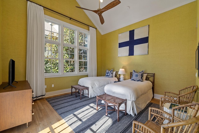 bedroom with wallpapered walls, vaulted ceiling, wood finished floors, and baseboards