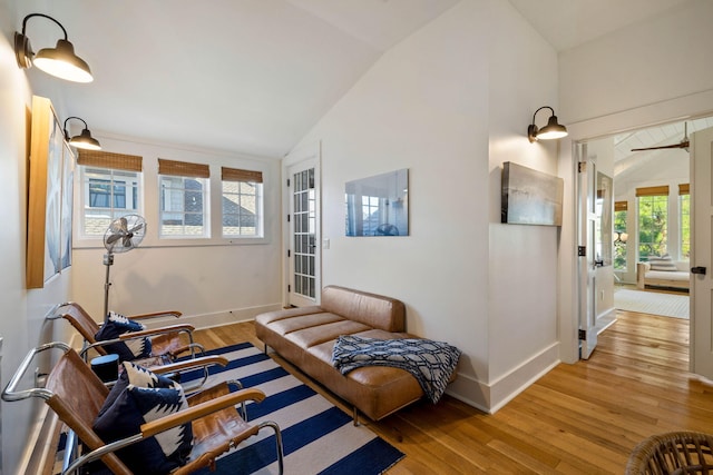 living area with vaulted ceiling, baseboards, and light wood finished floors