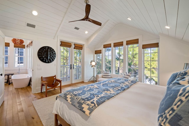 bedroom featuring hardwood / wood-style floors, visible vents, vaulted ceiling, access to outside, and multiple windows