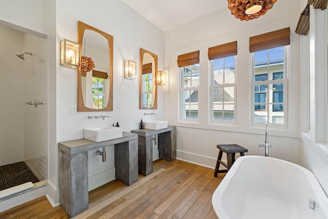 full bathroom with baseboards, tiled shower, wood finished floors, a soaking tub, and a sink