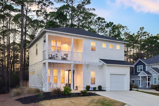 view of front of home featuring board and batten siding, a porch, driveway, a balcony, and an attached garage