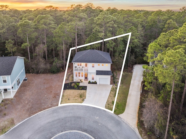 aerial view at dusk featuring a forest view