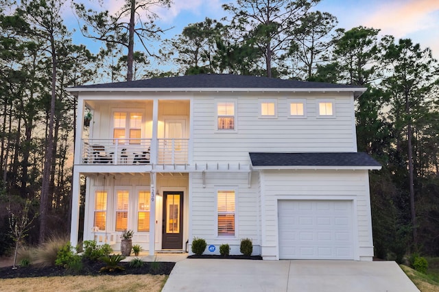 view of front of property with driveway, board and batten siding, roof with shingles, an attached garage, and a balcony