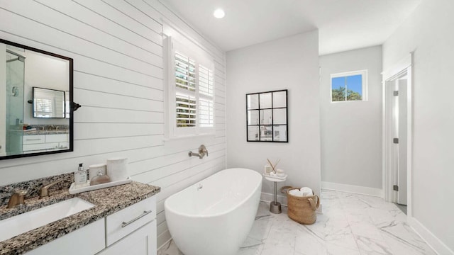 bathroom with plenty of natural light, marble finish floor, a freestanding bath, and vanity