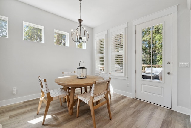 dining room with a notable chandelier, light wood-type flooring, and baseboards