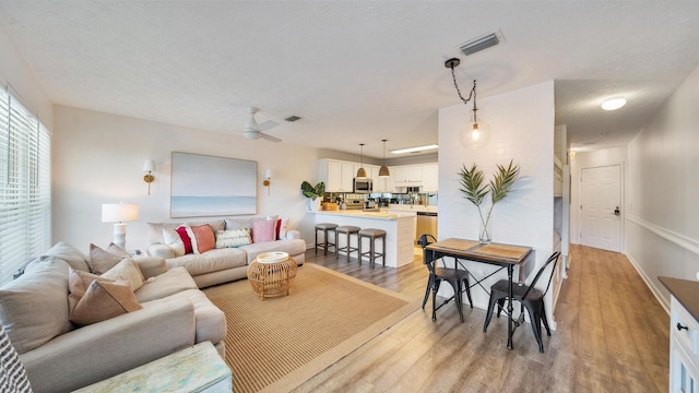 living area with visible vents, light wood-style flooring, and ceiling fan