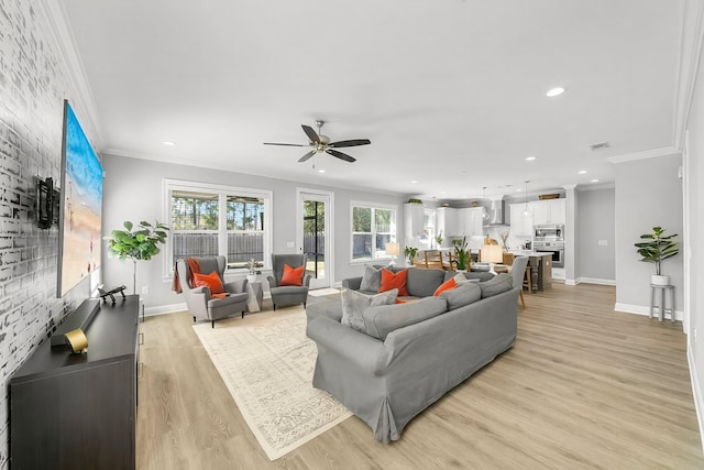 living area with baseboards, ornamental molding, a ceiling fan, and light wood-style floors