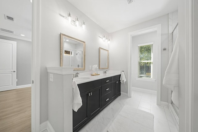 full bath with a sink, double vanity, visible vents, baseboards, and a shower with shower door