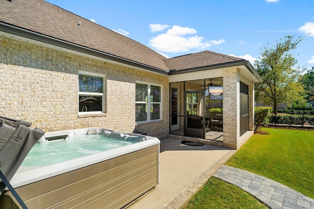 rear view of property with roof with shingles, a patio area, a hot tub, and a lawn