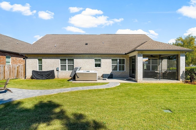 back of property featuring a sunroom, a patio, a lawn, a hot tub, and fence