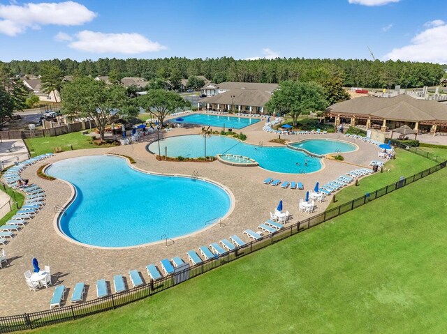 pool featuring a lawn, a view of trees, and fence