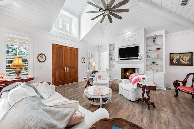 living area with visible vents, built in features, wood finished floors, a lit fireplace, and wood ceiling