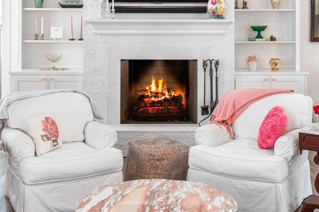 living area featuring built in features and a lit fireplace