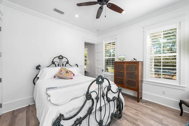 bedroom with visible vents, multiple windows, baseboards, and wood finished floors