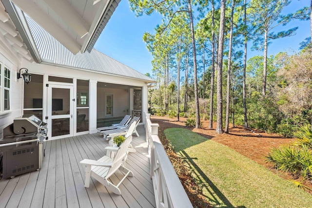 wooden deck featuring area for grilling, a yard, and a sunroom