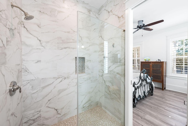 full bathroom featuring a ceiling fan, crown molding, wood finished floors, and a marble finish shower