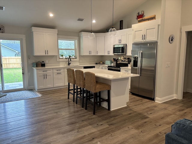 kitchen featuring white cabinets, a kitchen island, appliances with stainless steel finishes, and a sink