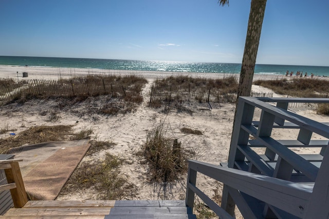 view of water feature featuring fence and a view of the beach