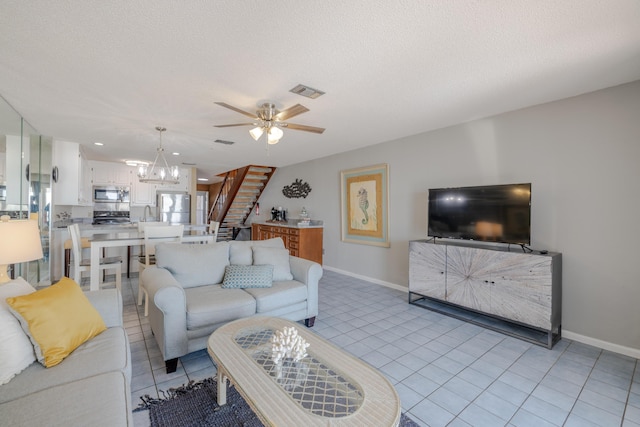 living area featuring stairway, light tile patterned flooring, visible vents, and a textured ceiling