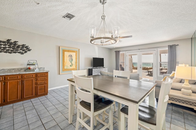 dining room featuring visible vents, a notable chandelier, a textured ceiling, french doors, and light tile patterned floors