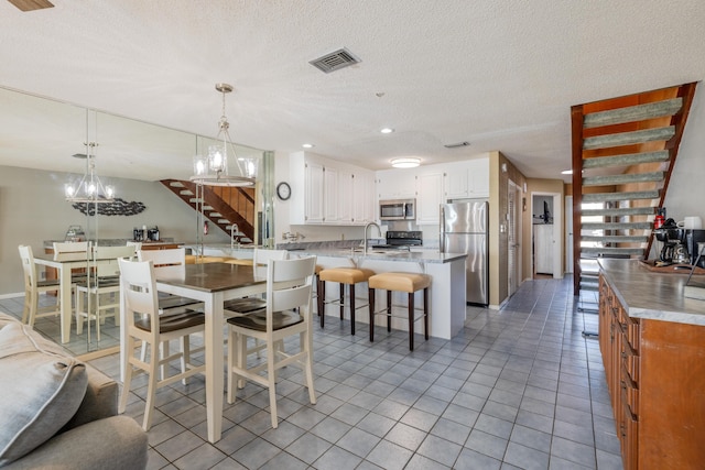 dining space featuring visible vents, a chandelier, stairs, light tile patterned flooring, and a textured ceiling