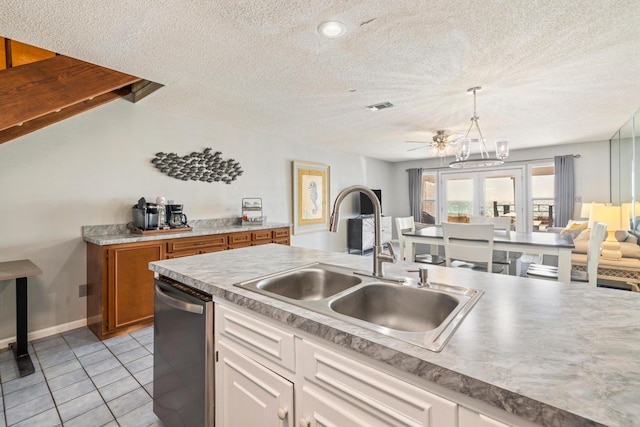 kitchen featuring visible vents, a sink, stainless steel dishwasher, open floor plan, and light tile patterned flooring