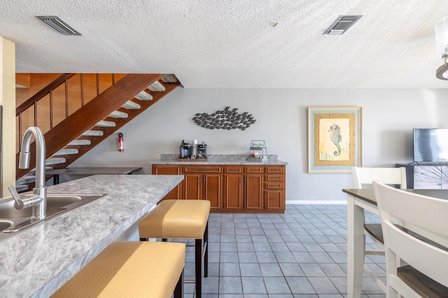 kitchen with a sink, visible vents, brown cabinets, and light countertops