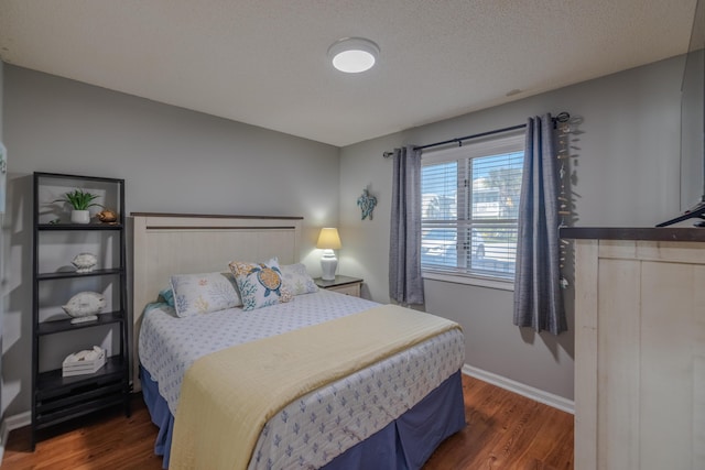 bedroom with baseboards, a textured ceiling, and wood finished floors