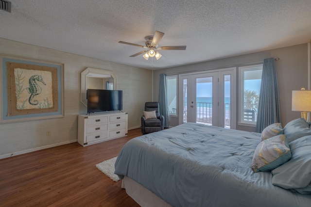 bedroom with ceiling fan, baseboards, wood finished floors, a textured ceiling, and access to outside