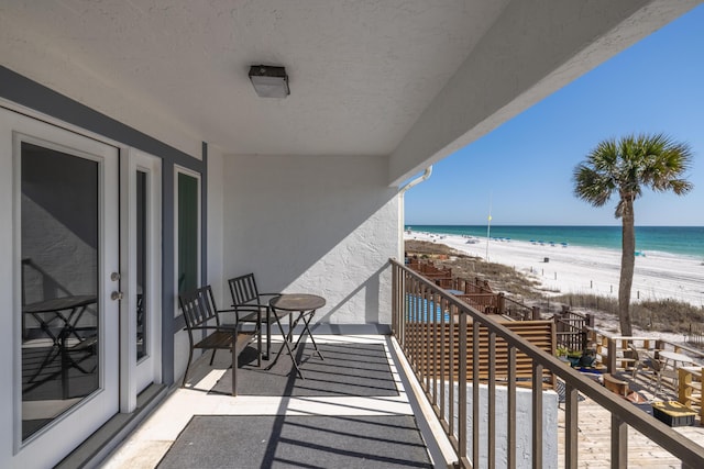 balcony featuring a view of the beach and a water view