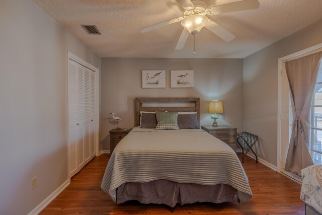 bedroom featuring visible vents, a textured ceiling, wood finished floors, a closet, and baseboards