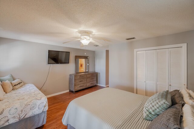 bedroom featuring visible vents, a ceiling fan, wood finished floors, a closet, and baseboards