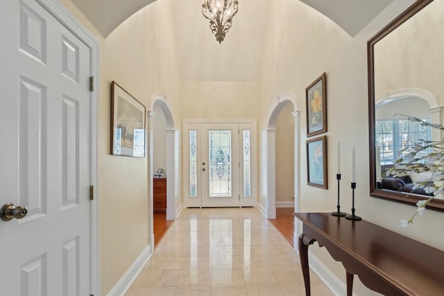 foyer entrance featuring arched walkways, baseboards, and a wealth of natural light