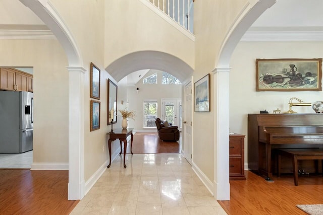 entryway with arched walkways, crown molding, and baseboards